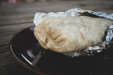 California Style Burrito in Flour Tortilla Wrapped in Foil on Plate
