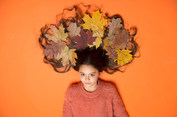 Haircare tips add to fall routine. Little girl gorgeous long hair and fallen maple leaves. Deep...