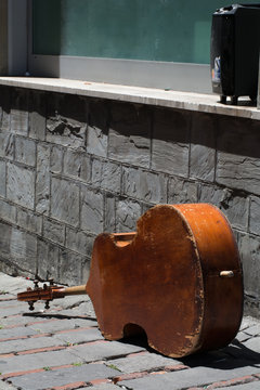 Violoncello abbandonato per strada assieme ad una valigia di plastica