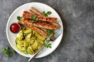 Grilled chicken sausages with zucchini salad in olive oil, soy sauce, wine vinegar, garlic and cilantro. Top view. 