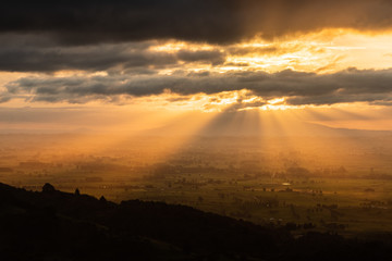 Amazing scenic sunset over endless rolling hills, villages and lakes. Beautiful sun rays peaking through the clouds. Colorful and vivid scene, peaceful and relaxing.