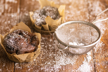 Tasty chocolate muffins in powdered sugar