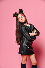 hipster punk girl - dressed in a leather jacket and skirt, with a funny hairstyle and a makeup painted star on her face, folded her arms across her chest and looks behind her