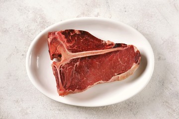 Fresh raw organic beef t-bone steak on a light background. Top view. 