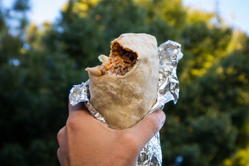 Holding a Burrito with a Bite Out of It in California