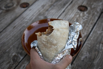 Holding a Burrito with a Bite Out of It in California