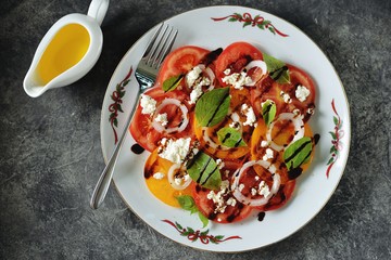 Salad of yellow and pink tomatoes with basil, soft cheese, onions, olive oil and balsamic cream.