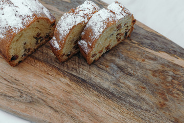Raisin cake, dusted with icing sugar. Cupcake with raisins on a wooden board