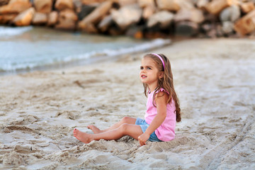 little girl having fun at the beach and looking at the sky