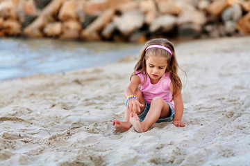 little girl having fun at the beach and playing with sand