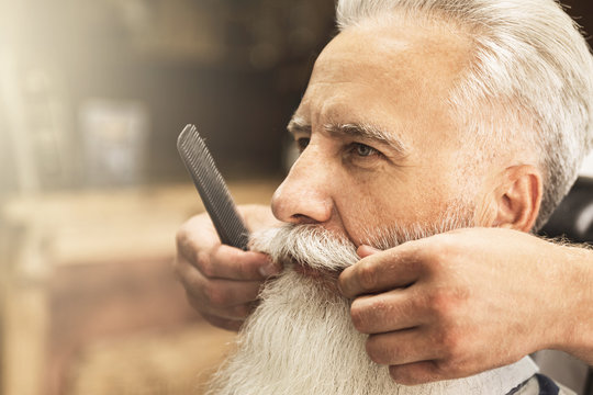 Handsome senior man getting styling and trimming of his beard