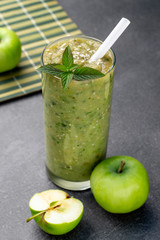Green apple smoothie in a glass, whole and half apple