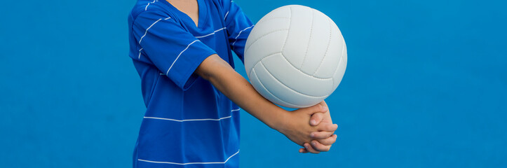 Boy playing volleyball isolated in blue.
