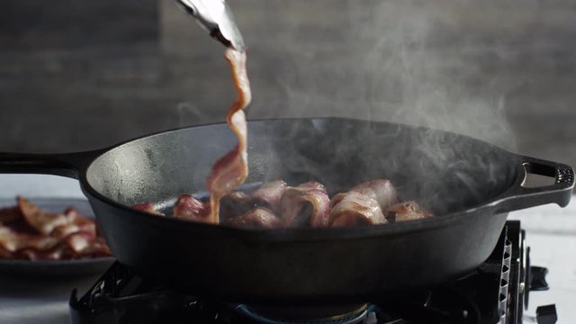 Slow motion, cooking bacon close up