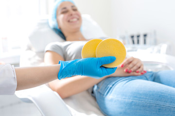 the hand of the beautician holds the massage pad against the background of a happy patient