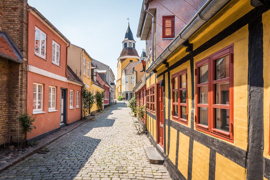 An alleyway with cobblestones and half timbered houses, leading up to the church in Faaborg