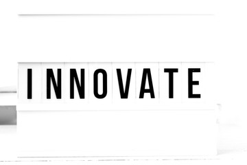 Innovate flat lay on a wooden white background. Motivational business start up board