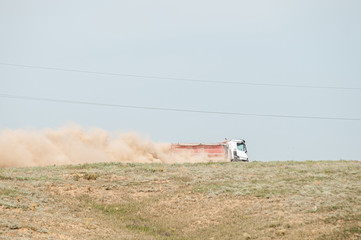 truck driving on sandy road picking up dust