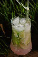 refreshing summer cocktail with lime, green and ice on a green summer background. mahito in a glass