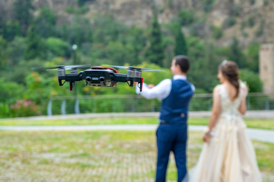 Hovering drone shooting young couple on their wedding in nature.