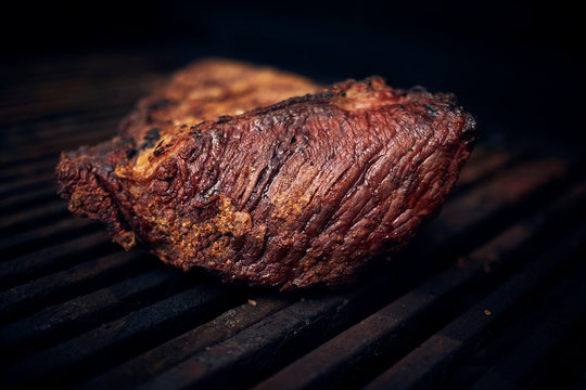 Grilled meats over the barbecue fire. You can see the smoke, the fire and the heat as well as the fiery ones of the melted fats when falling under the direct fire