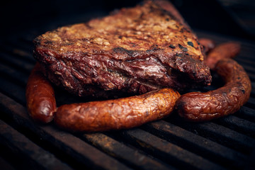 Grilled meats over the barbecue fire. You can see the smoke, the fire and the heat as well as the fiery ones of the melted fats when falling under the direct fire