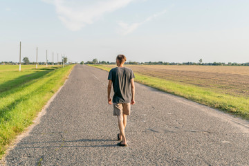 Fototapeta premium Young guy walking on the road in the open
