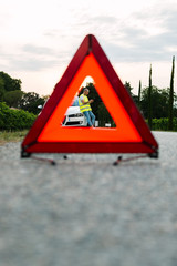 Red emergency stop sign and young man waiting the car assistance with broken car on the road