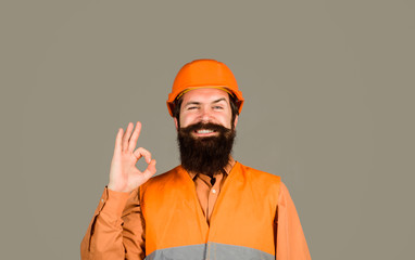 Repair, construction, building. Male builder or manual worker in helmet shows ok sign. Mechanical worker making gesture okay. Construction worker in hard hat. Bearded man in hardhat with perfect sign.