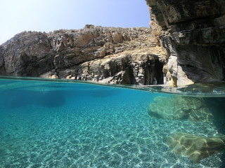 Fototapeta na wymiar Above and below underwater photo of crystal clear sea paradise rocky seascape full of caves beach of Mouros, Amorgos island, Cyclades, Greece