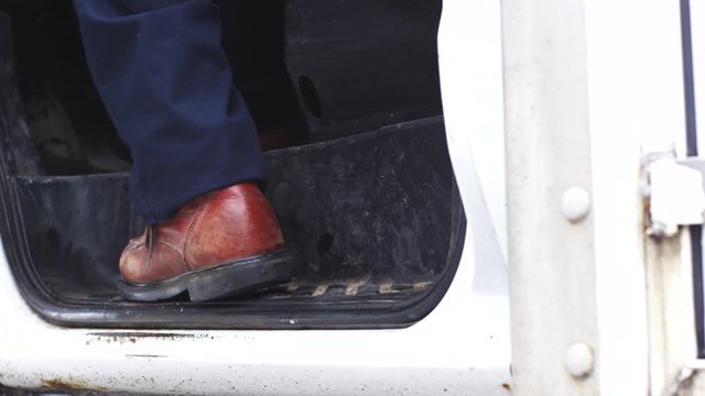 Low angle slow motion, person with work boots enters vehicle and closes door