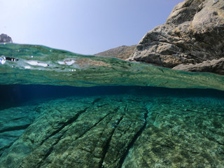 Above and below underwater photo of crystal clear sea paradise rocky seascape and small chapel of Agia Anna just next to iconic Hozoviotissa Monastery, Amorgos island, Cyclades, Greece