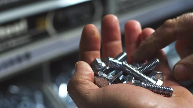 Slow motion close up, hex bolts in hand