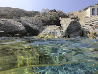 Above and below underwater photo of crystal clear sea paradise rocky seascape and small chapel of Agia Anna just next to iconic Hozoviotissa Monastery, Amorgos island, Cyclades, Greece