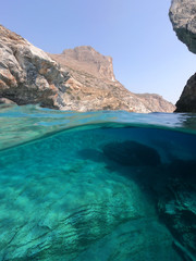 Above and below underwater photo of crystal clear sea paradise rocky seascape and small chapel of...