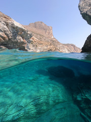 Above and below underwater photo of crystal clear sea paradise rocky seascape and small chapel of Agia Anna just next to iconic Hozoviotissa Monastery, Amorgos island, Cyclades, Greece