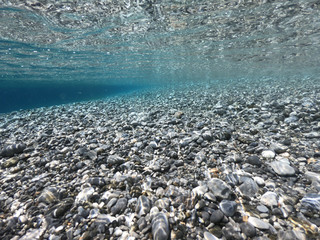 Above and below underwater photo of crystal clear turquoise beach of Kaminakia, Astypalaia island, Dodecanese, Greece