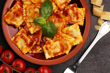 Ravioli with tomato sauce garnished with parmesan cheese and basil on rustic table