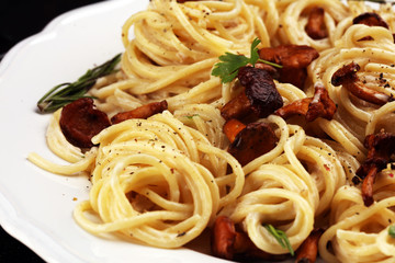 pasta with organic chanterelles. portion of spaghetti pasta with fried chanterelles in a creamy garlic sauce with cheese on a table