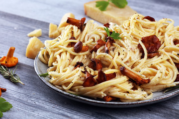 pasta with organic chanterelles. portion of spaghetti pasta with fried chanterelles in a creamy garlic sauce with cheese on a table