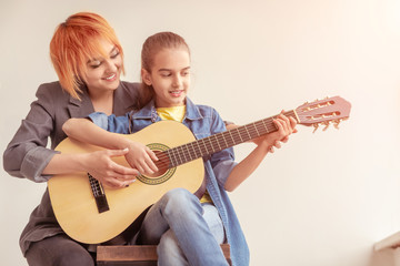 Woman teaching girl to play guitar