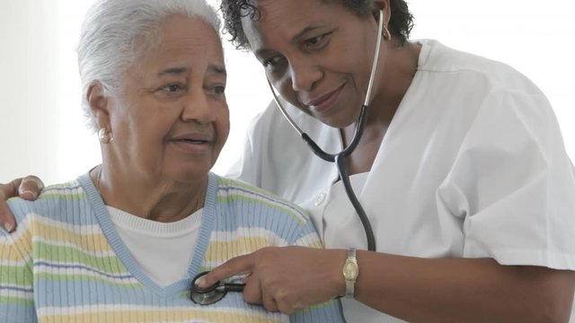 African American nurse checking senior patientÕs heartbeat