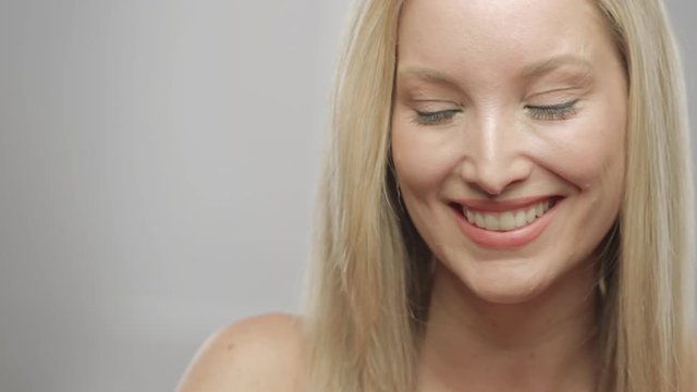 Caucasian blonde woman in studio smiling and laughing at camera