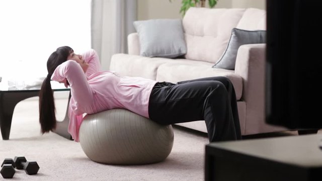 Asian woman doing sit-ups on fitness ball