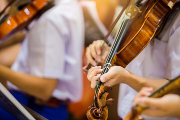 Asian boy students playing violin with music notation in the group. Violin player. Violinist hands...