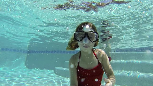 Caucasian girl with goggles swimming underwater