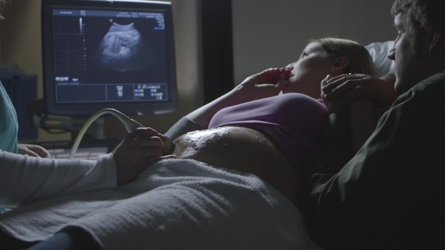 Pregnant Caucasian couple watching ultrasound