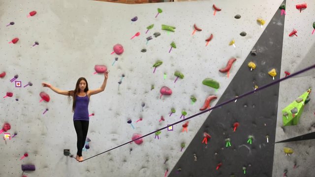 Mixed race girl walking on slackline at indoor climbing gym