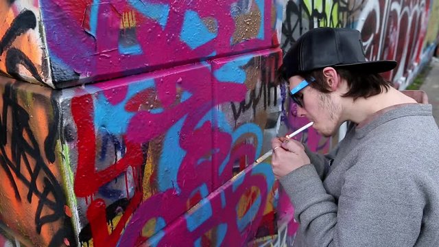 Caucasian boy painting graffiti on wall