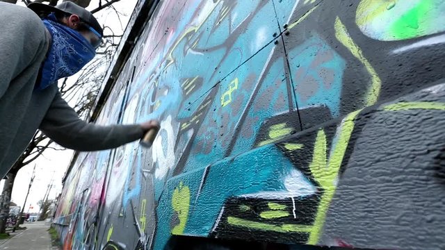 Caucasian boy with bandana painting graffiti on wall